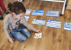 Dzieci układają kolejne litery aby ułożyć napis Grecja.